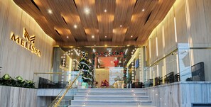 A modern interior with a wooden ceiling, a staircase leading to a reception area, and a Christmas tree.