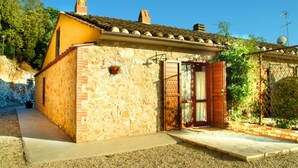 Un bâtiment en pierre avec un toit recouvert de tuiles, une porte et un petit jardin.