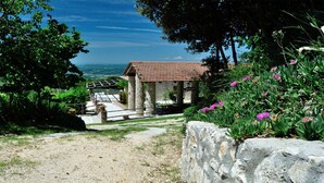Un bâtiment en pierre, doté d’un toit en tuiles, entouré de verdure et offrant une vue dégagée sur le paysage.