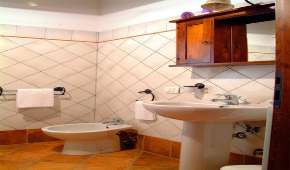 A bathroom with a bidet, a sink, and a wooden cabinet above the sink.