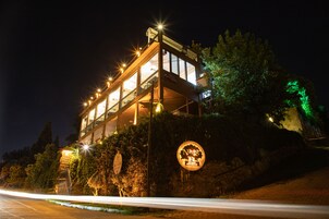 Un immeuble à plusieurs étages, doté de fenêtres illuminées et d’une enseigne indiquant la présence d’un restaurant.