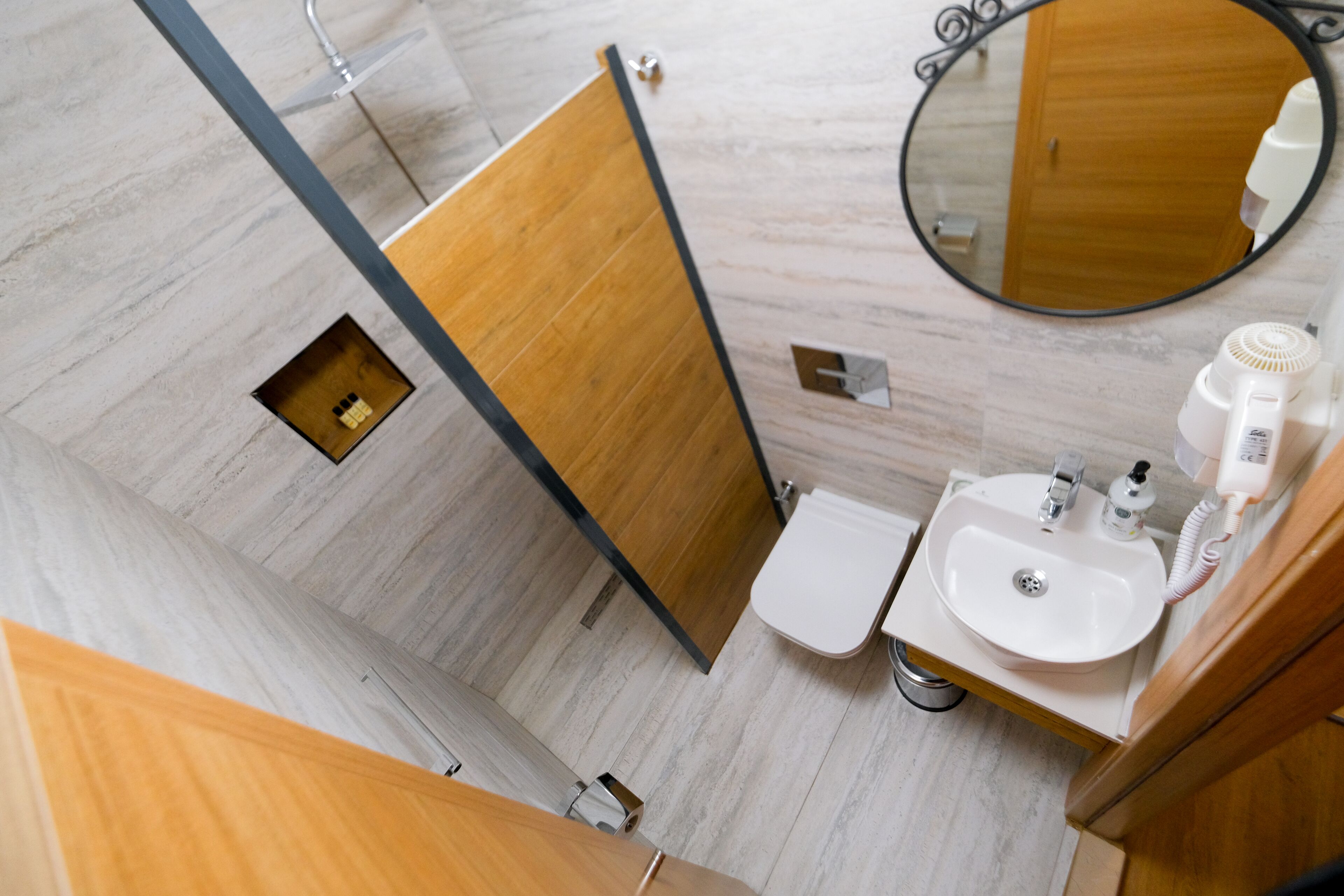 A modern bathroom with a wooden vanity, a white sink, a mirror, and a toilet.
