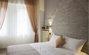 Een slaapkamer met een bed, een radiator, een bakstenen muur en een raam met gordijnen.