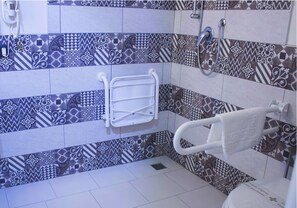 Een badkamer met patroon betegelde vloertegels, een witte handdoekhouder en een douchehoek.