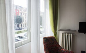 Een kamer met een raam, een radiator en een stoel.