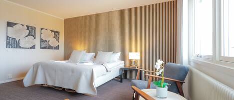 Una habitación de hotel con cama, escritorio, silla y ventana.