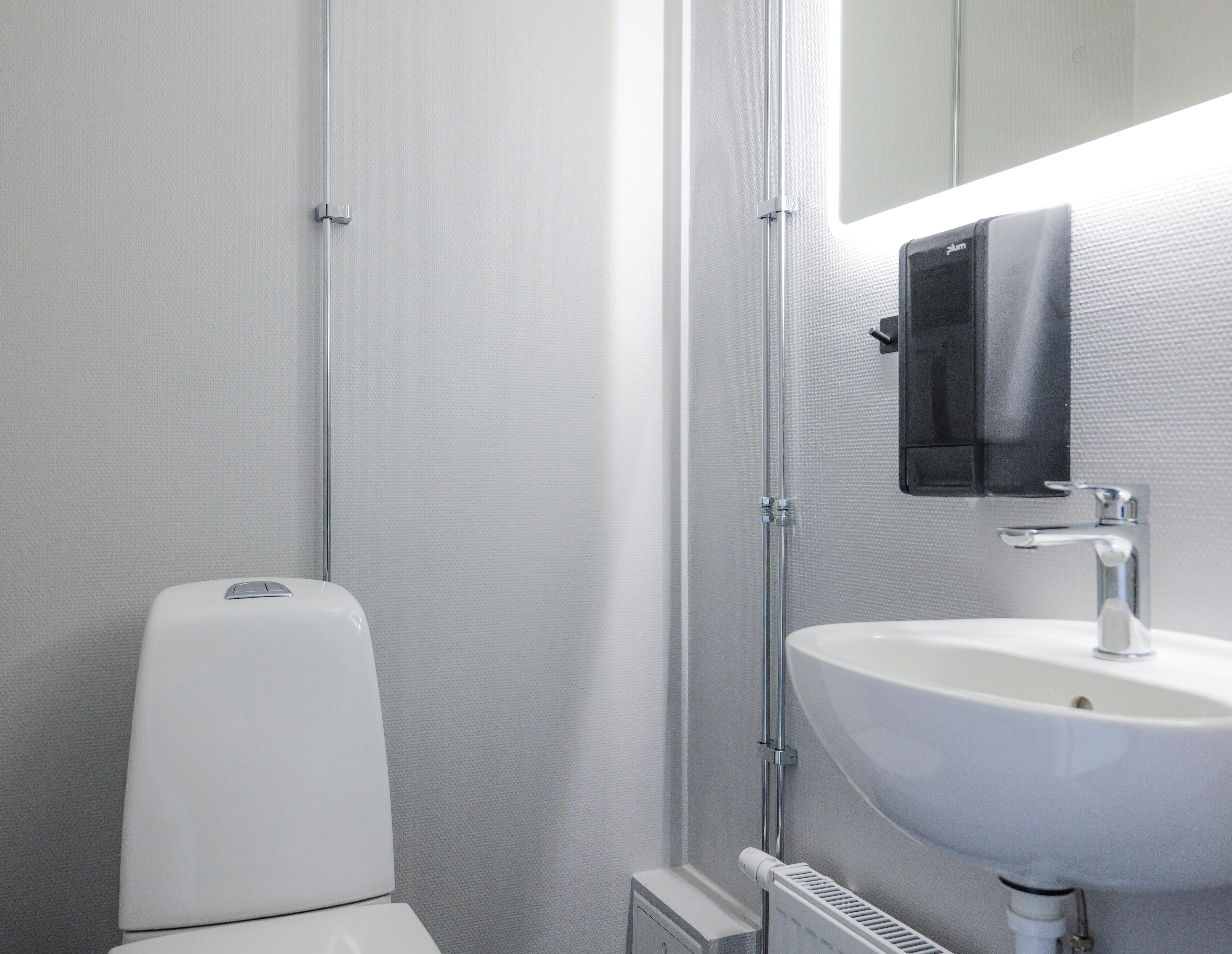 A modern bathroom with a white toilet, a sink, and a mirror.