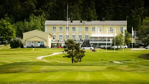 Ein Golfplatz mit Klubhaus und einem großen Gebäude im Hintergrund.