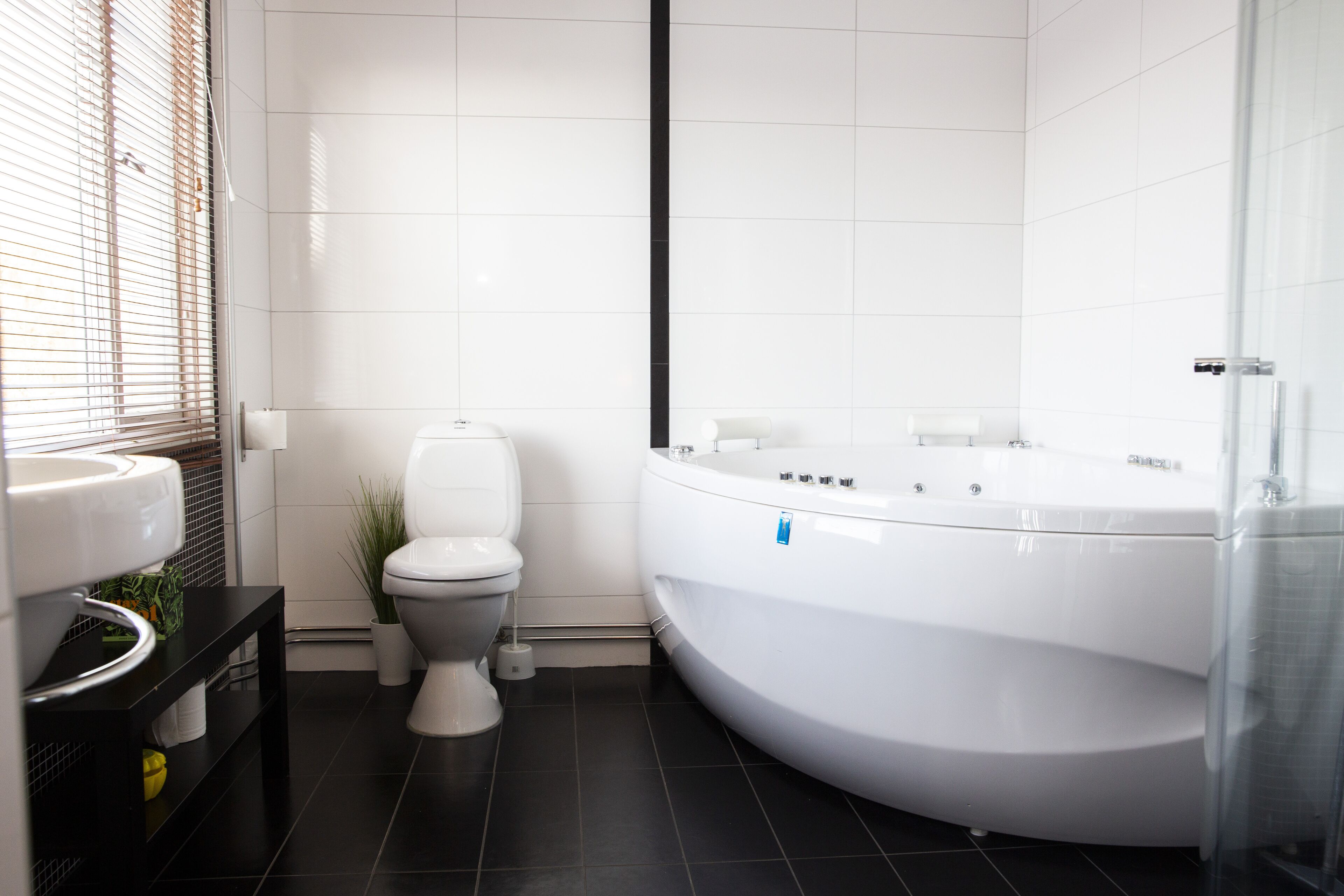 A modern bathroom with a toilet, sink, and a large bathtub.