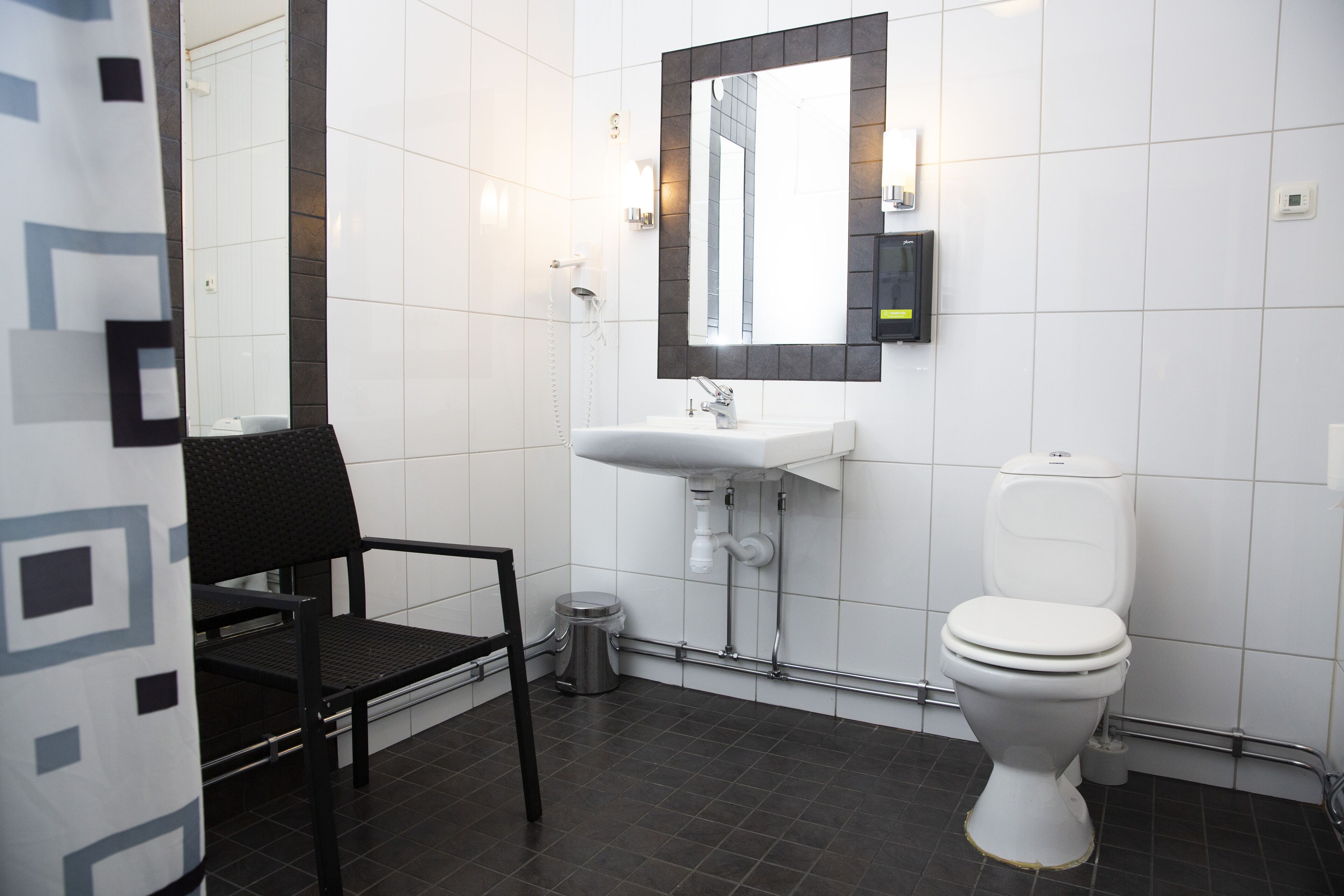 A modern bathroom with a white sink, a toilet, and a chair.