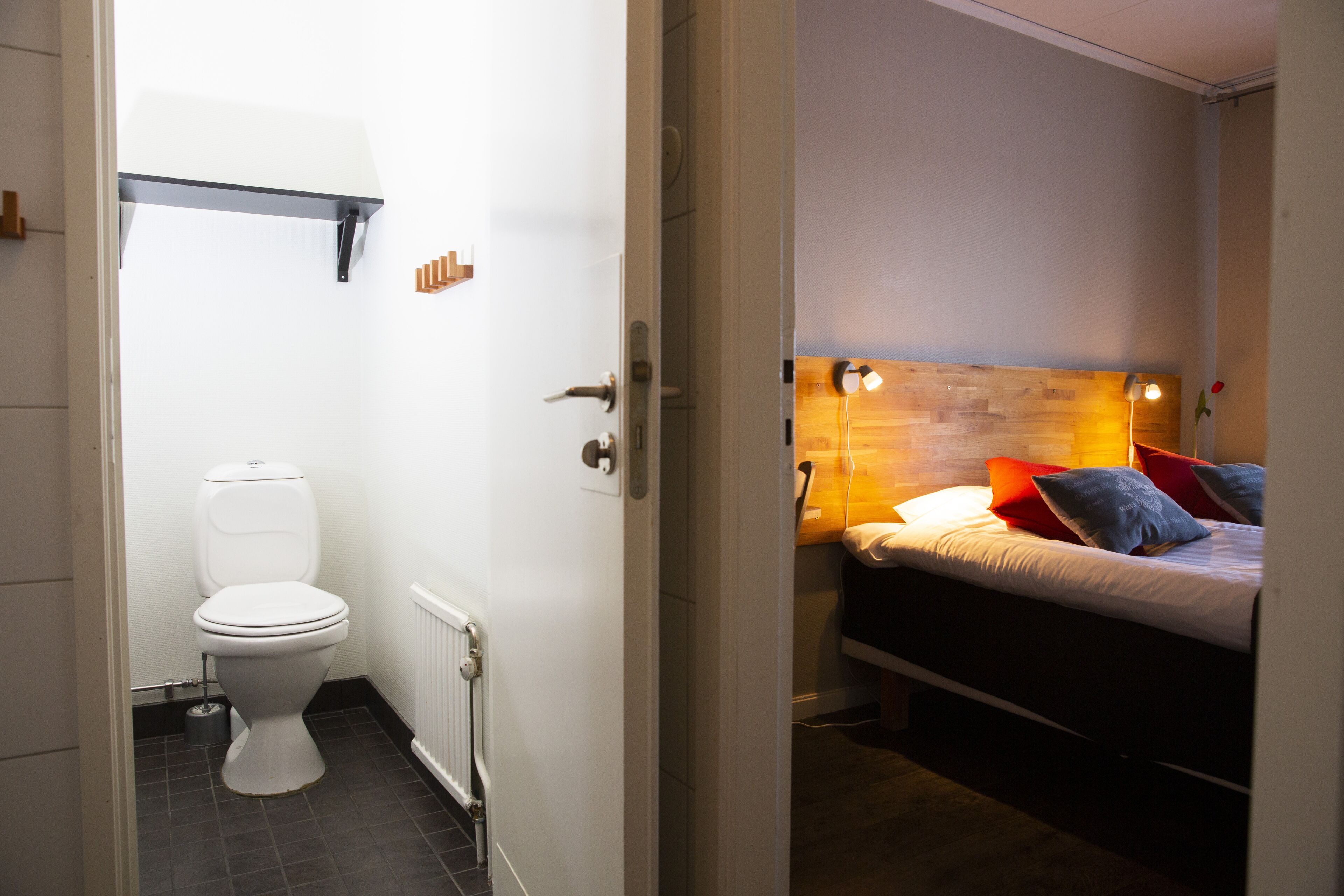 Un baño con inodoro y cama con almohadas.