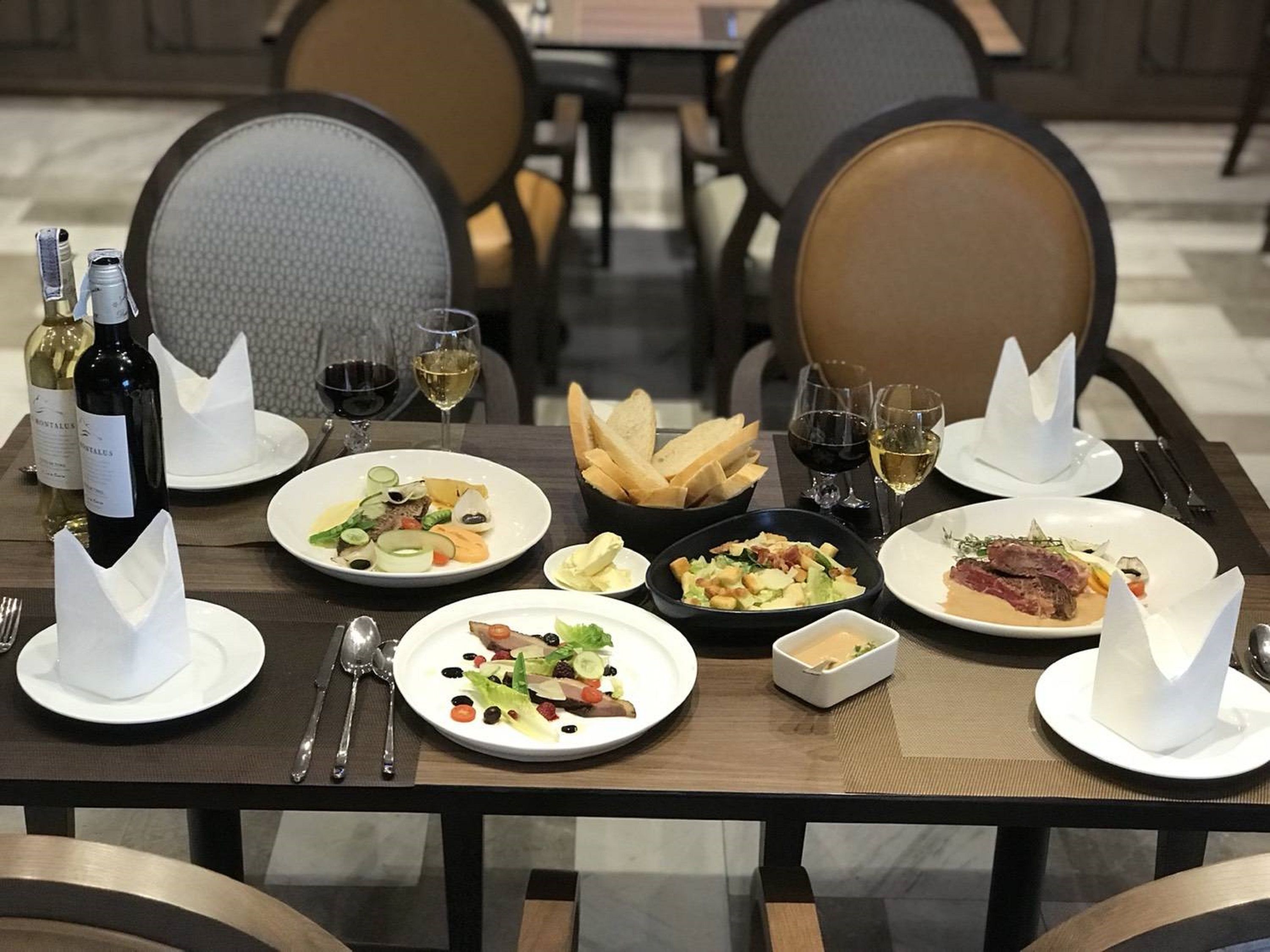 A dining table set with various dishes, wine glasses, and cutlery, indicating a restaurant setting.