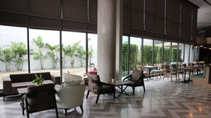 Un espacio interior amplio con ventanas grandes, mobiliario moderno y un patrón de suelo tipo espiga.