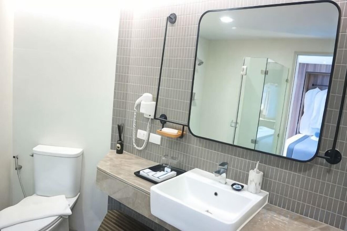A bathroom with a toilet, sink, mirror, and towel rack.
