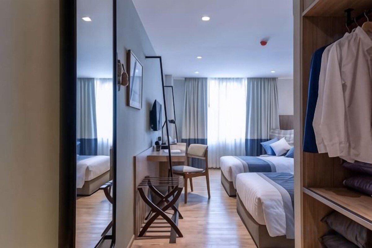 A hotel room with a bed, a desk, a chair, and a wardrobe.