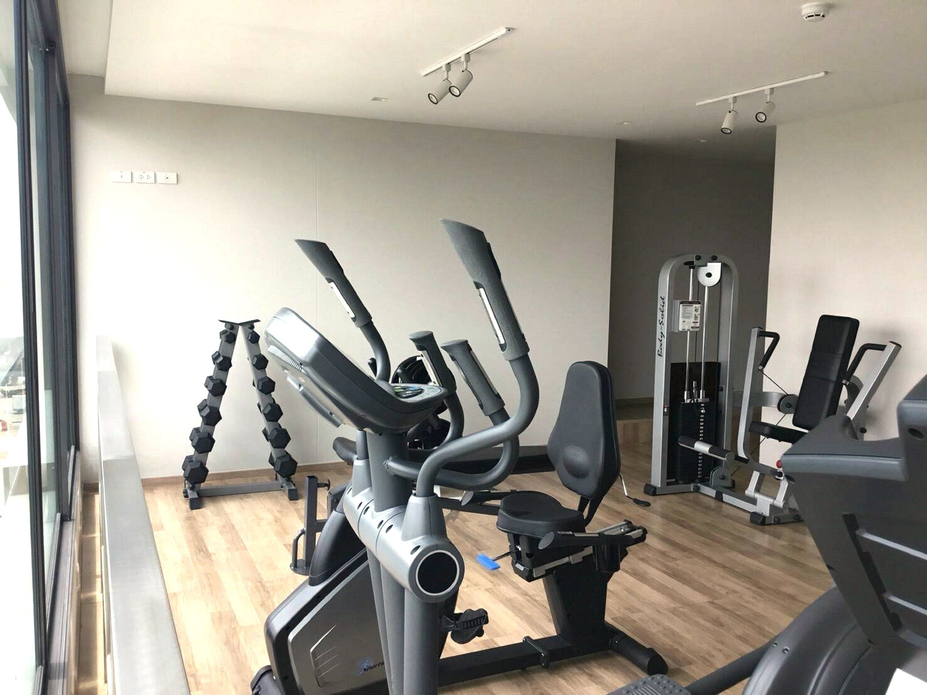 A gym with cardio machines, weight machines, and a mirrored wall.