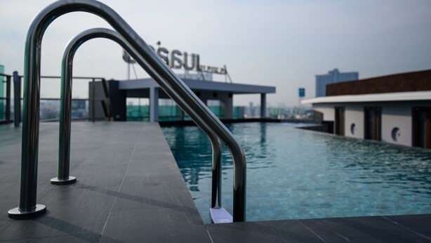 Una piscina con barandales de metal y un edificio al fondo.