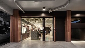 A modern building entrance with a reception desk, a car parked outside, and a staircase leading to an upper level. - Waterfront Hotel (Taipei)