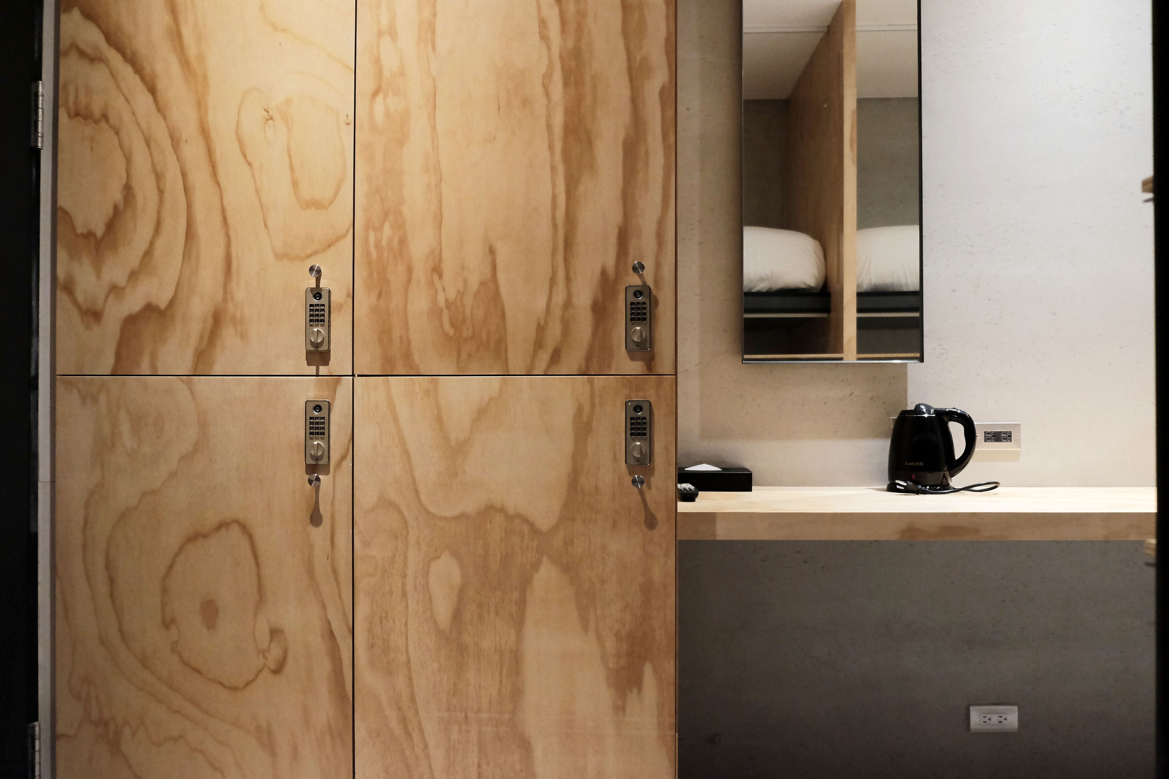 A wooden wardrobe with a mirror and a small shelf with a kettle.