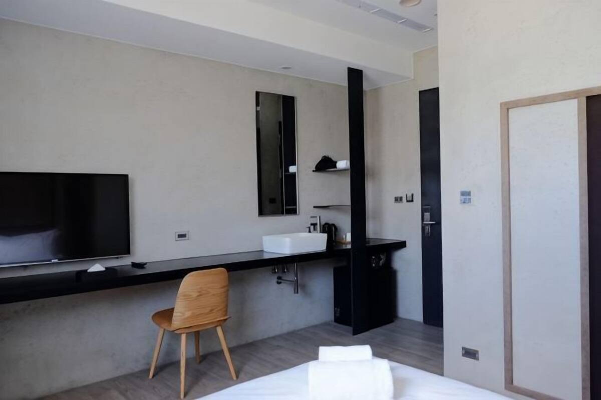 Una habitación de hotel con cama, televisión, escritorio con silla, espejo y puerta.