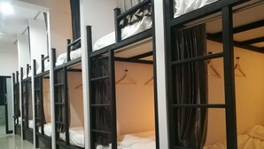 Varias literas con estantes de almacenamiento y espacio para colgar, en una habitación luminosa con piso de baldosas.
