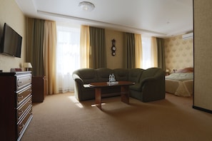 Une chambre d’hôtel avec un canapé, une petite table, une télévision, une commode et un lit.