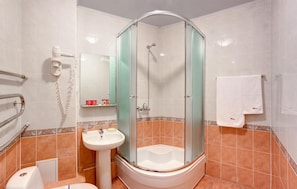 Une salle de bain moderne avec une douche à parois de verre, un lavabo sur colonne et des toilettes.