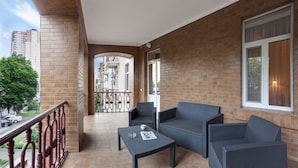 A balcony with wicker furniture, a tiled floor, and a view of a building in the background. - Hotel Oberig Kiev (Kyiv)