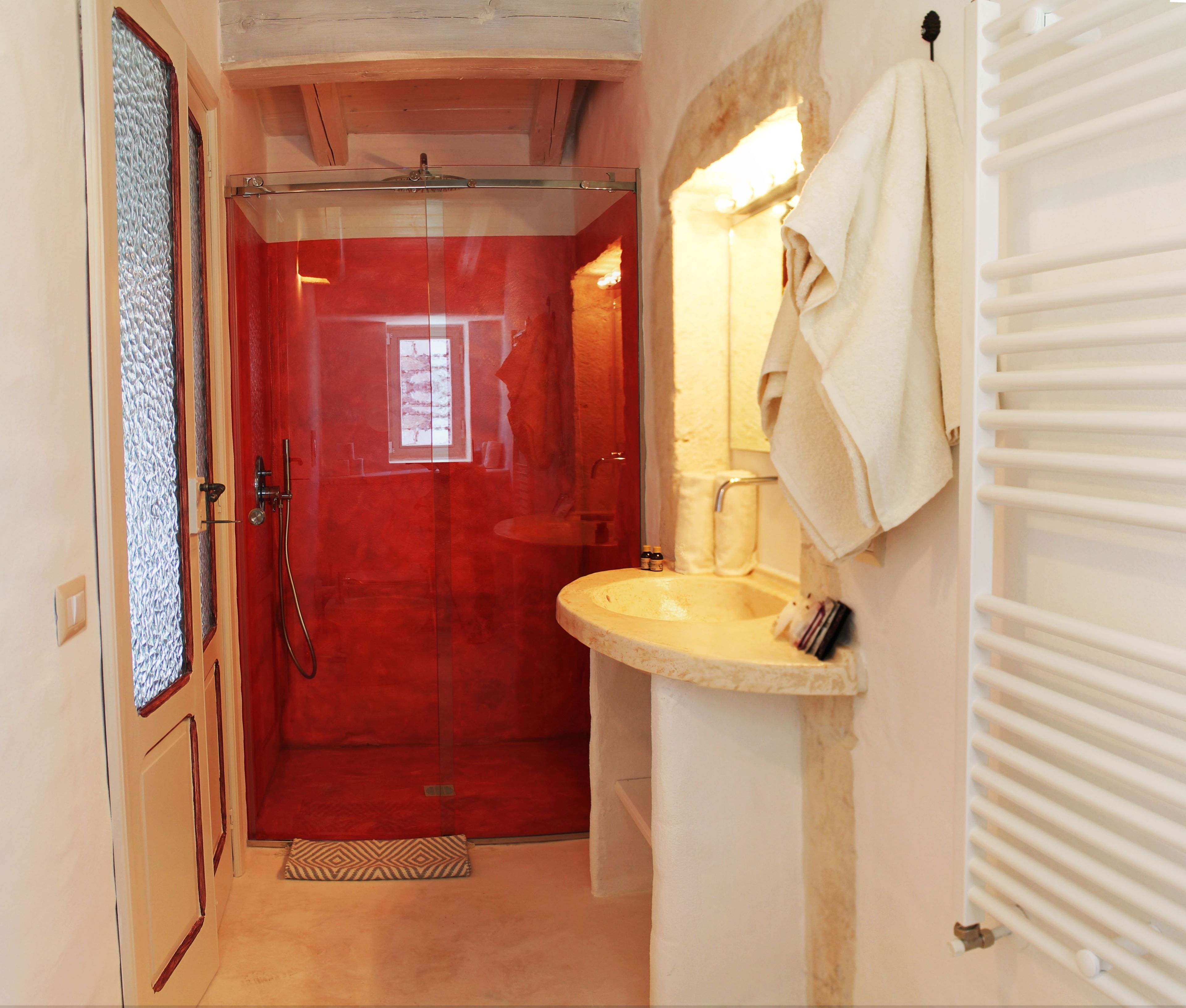 Une salle de bain avec une douche à parois de verre, un lavabo et une serviette accrochée au mur, ainsi qu’un radiateur.