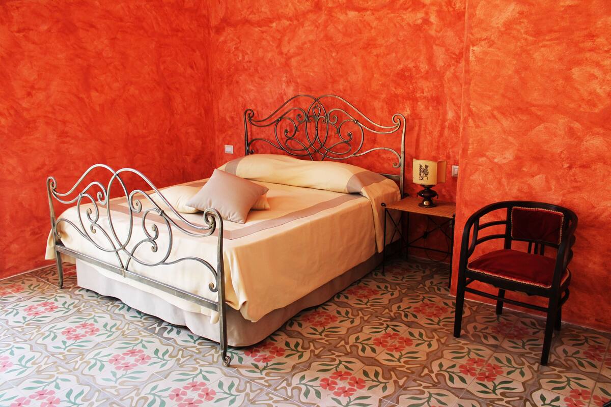 A room with a bed, a chair, and a nightstand.