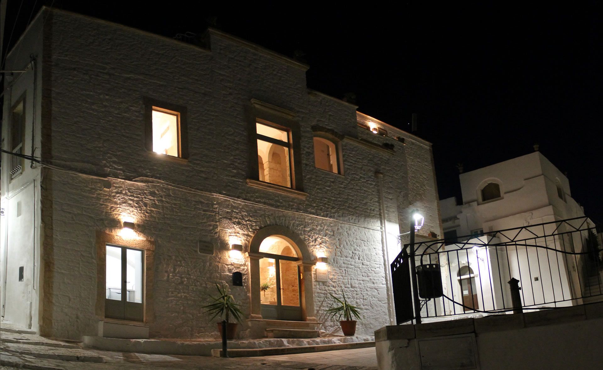 Ein Gebäude aus Stein mit beleuchteten Fenstern und einem verschlossenen Eingang bei Nacht.