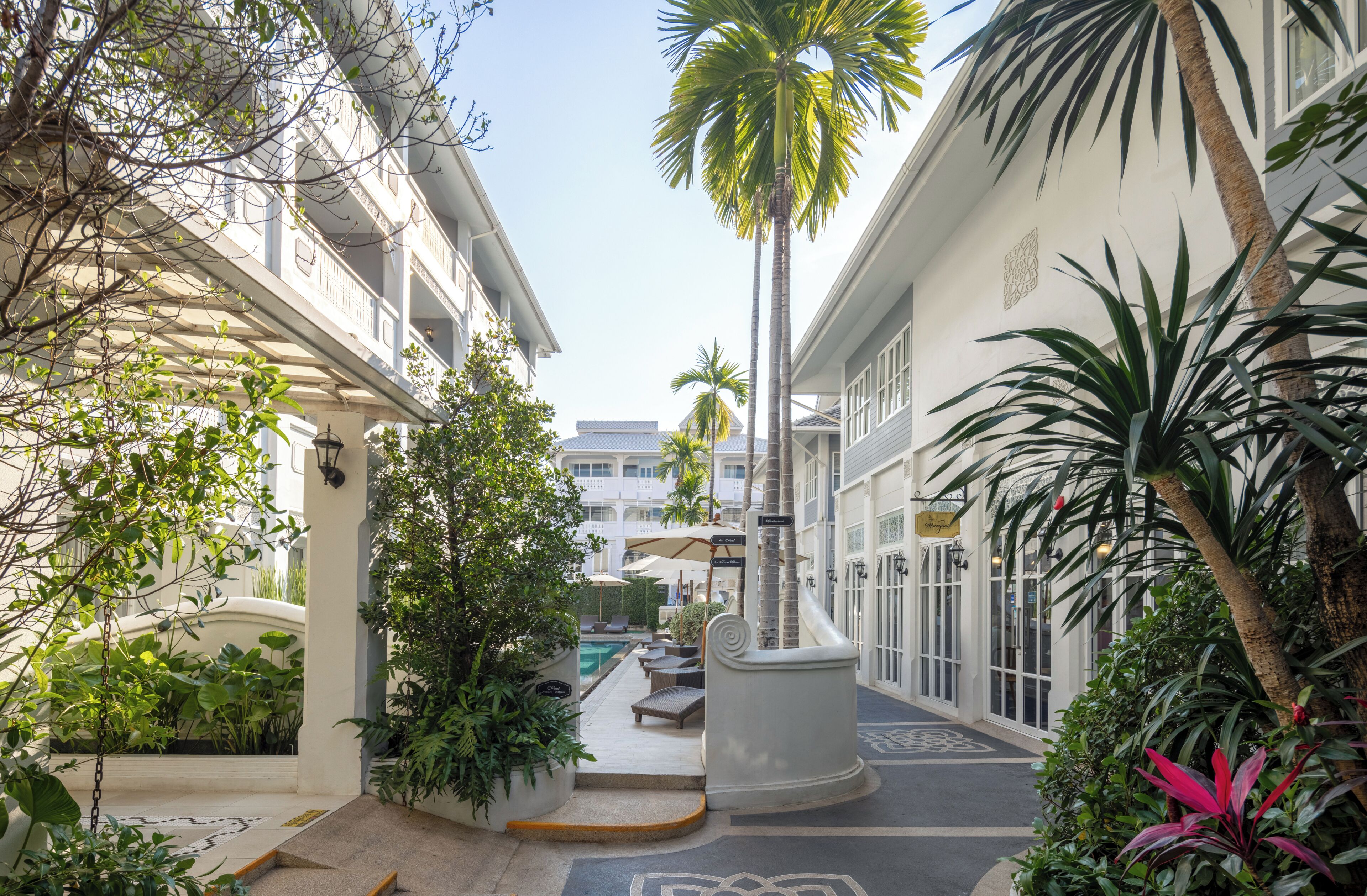A hotel courtyard with a pool, palm trees, and lounge chairs.