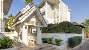 A white building with a sloped roof, a staircase, and a hedge. - Away Chiang Mai Thapae Resort - A Vegan Retreat (Chiang Mai)