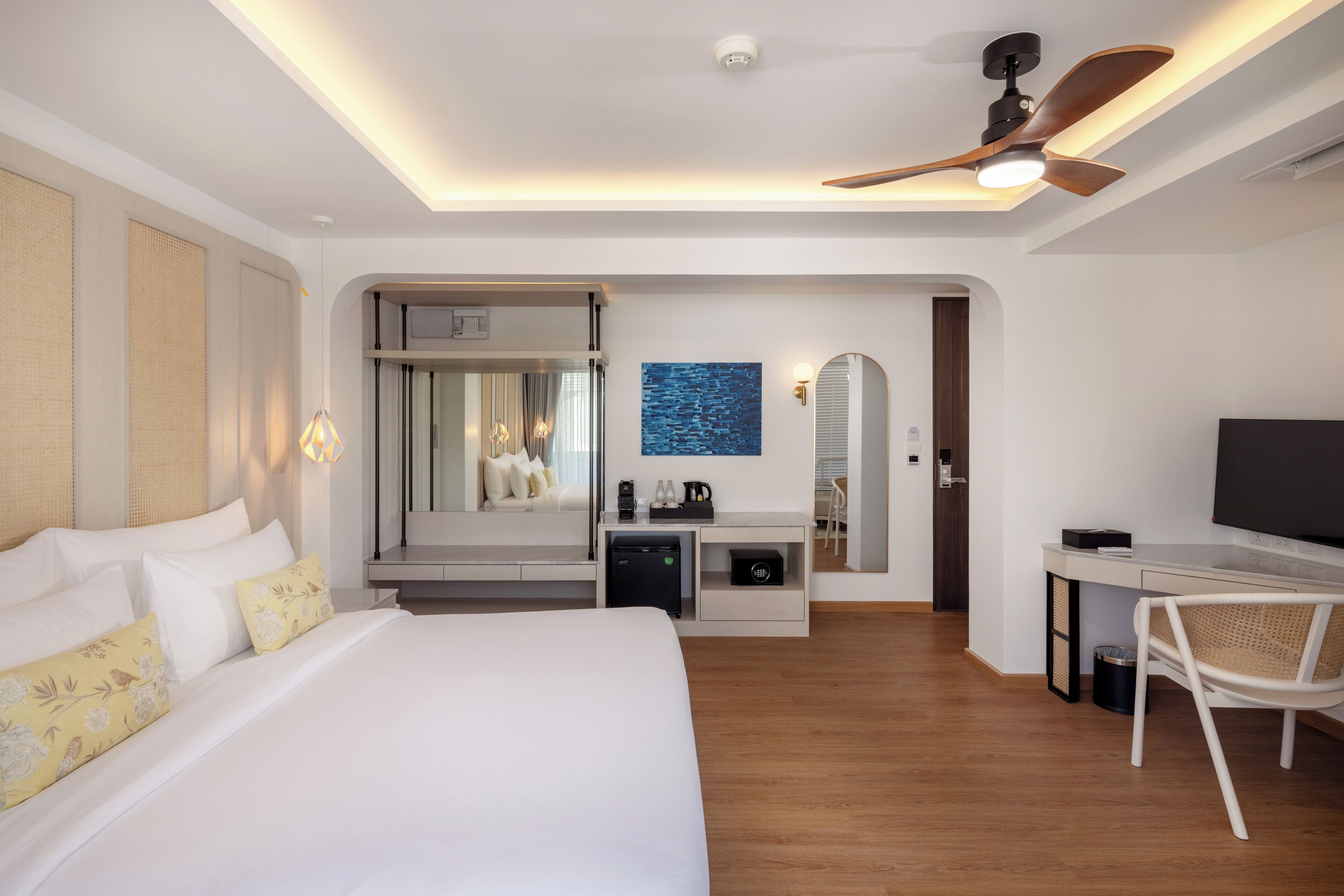 Una habitación de hotel moderna con una cama grande, un escritorio, un televisor y un ventilador de techo.