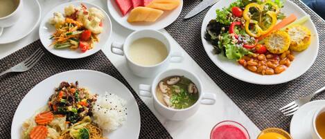 A table set with various dishes, including rice, noodles, soup, and a salad, along with drinks and condiments.