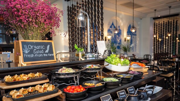 A buffet with various food options, a sign for organic salad, and a decorative vase of flowers. - Away Chiang Mai Thapae Resort - A Vegan Retreat (Chiang Mai)
