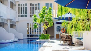 A pool area with a slide, outdoor seating, and a large umbrella. - Away Chiang Mai Thapae Resort - A Vegan Retreat (Chiang Mai)