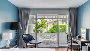A hotel room with a bed, a desk, a chair, a lamp, and a view of the outside. - Away Chiang Mai Thapae Resort - A Vegan Retreat (Chiang Mai)