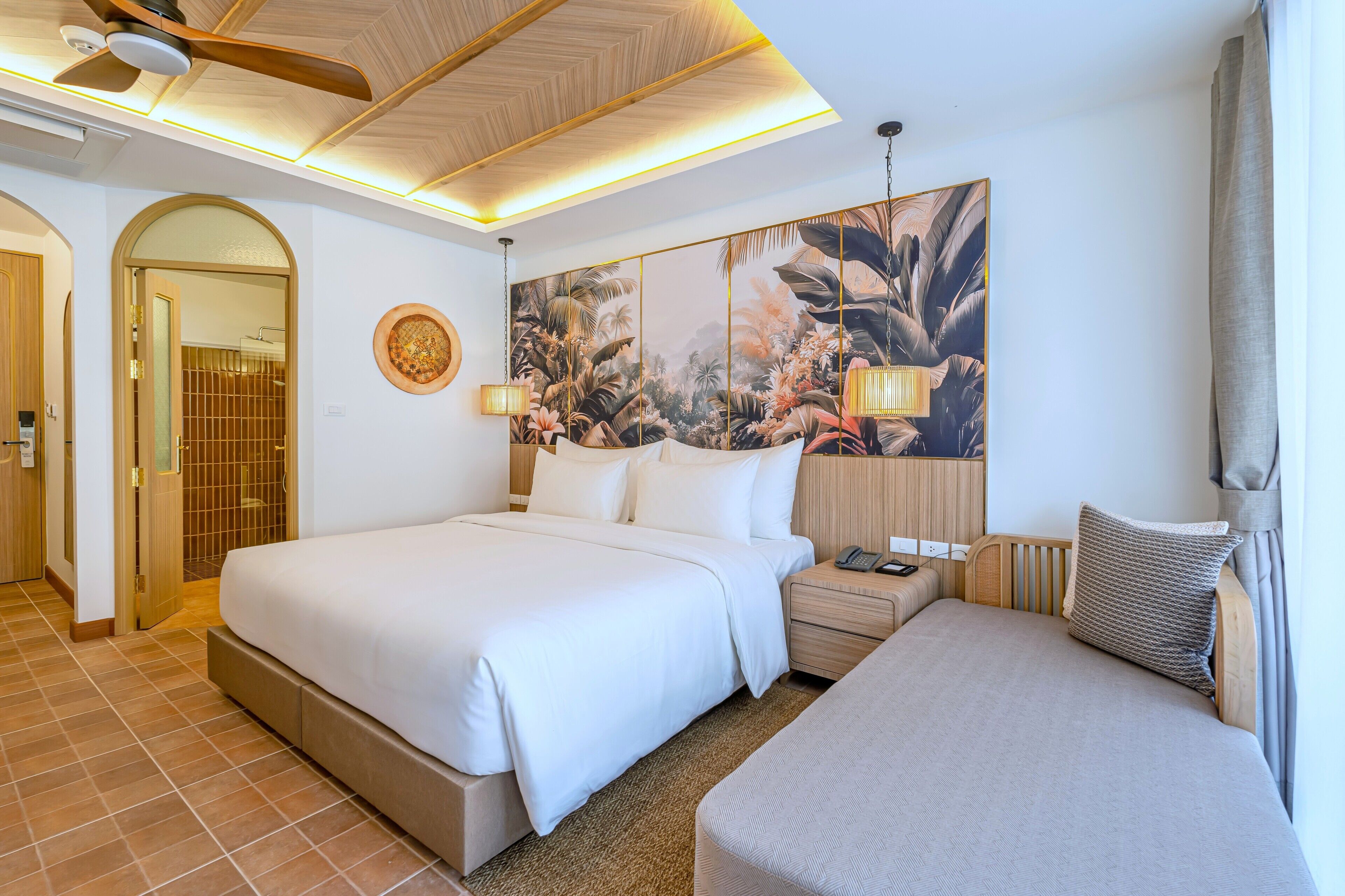 A hotel room with a large bed, a smaller bed, a nightstand, a wall-mounted lamp, and a large floral artwork.