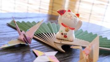 A decorative cat figurine on a table with origami figures and a fan.