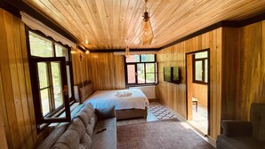 A wooden cabin bedroom with a bed, a sofa, and a TV. - Abant Yeşil Vadi (Bolu)