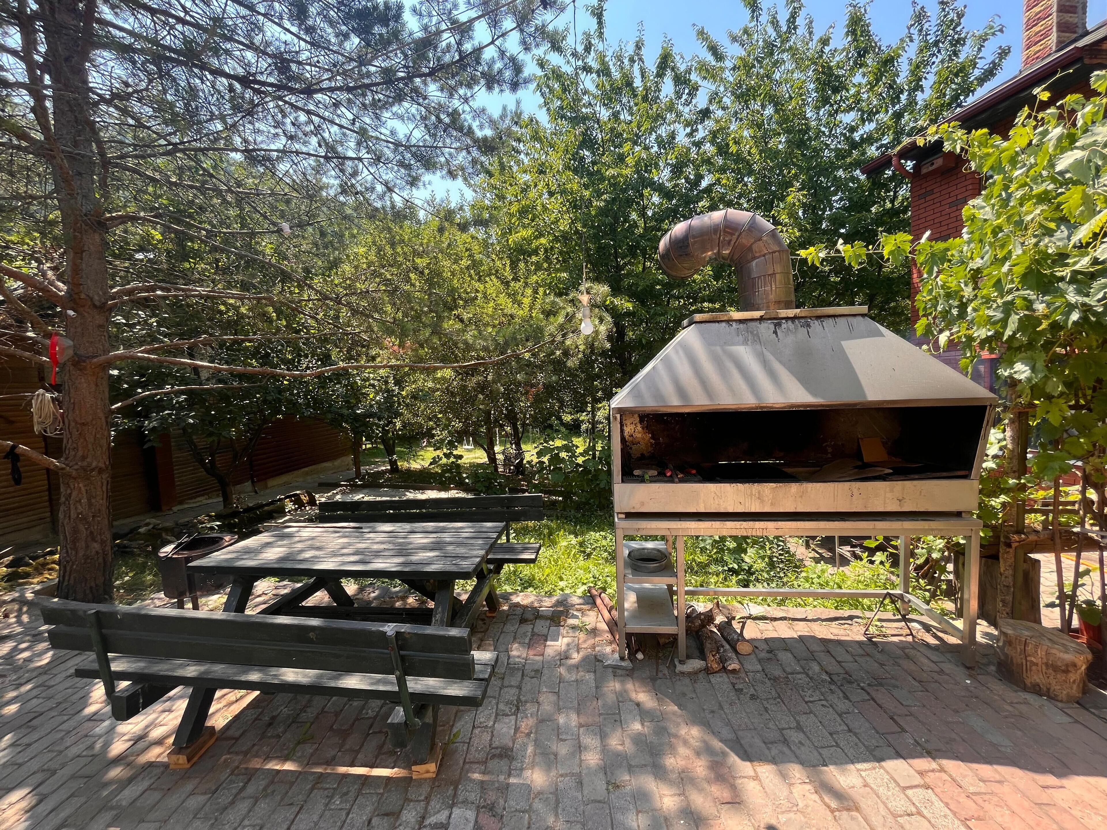 Un patio al aire libre con mesas de picnic y un horno de pizza a leña.
