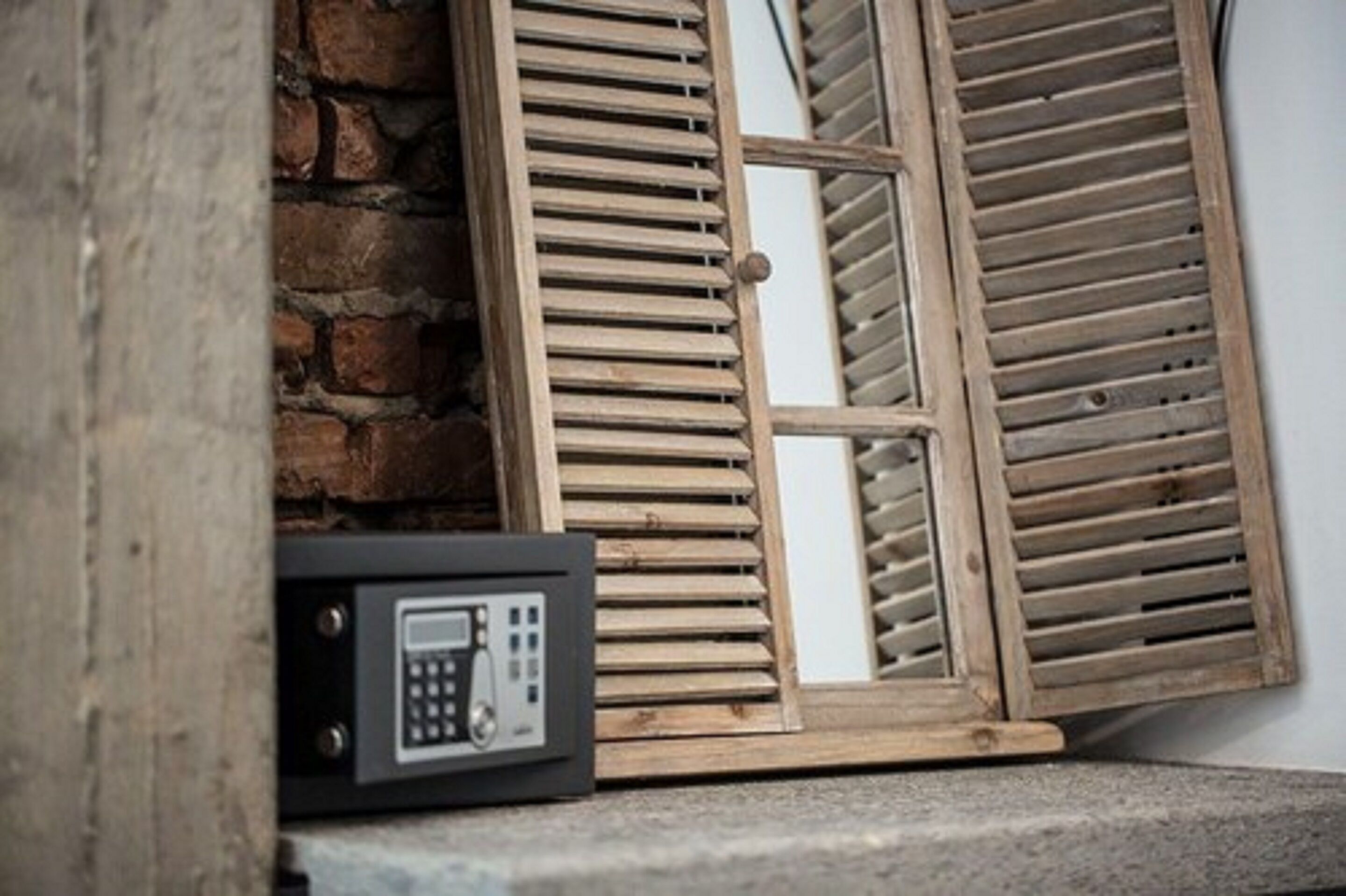 Un pulsante di sicurezza accanto a una porta con persiana in legno.