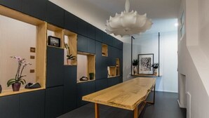 A modern interior with a long wooden table, dark walls, and built-in shelves with decorative items. - The Boutique Napoli Suite (Naples)