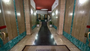 A hallway with a tiled floor, wooden walls, and a red ceiling. There are potted plants and a sign that reads "CONDOMINIO VIA ROMA 156". - The Boutique Napoli Suite (Naples)