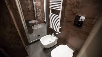A modern bathroom with a glass shower enclosure, a white sink, and a toilet.