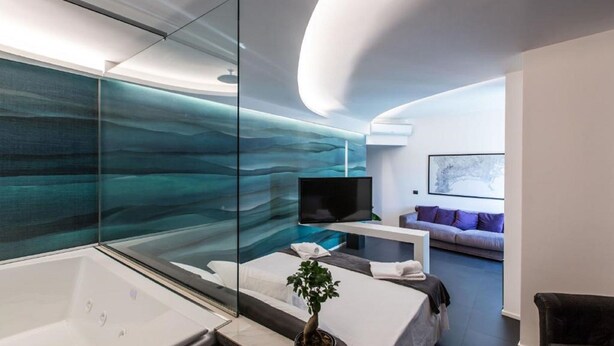 A modern bathroom with a glass-enclosed shower, a large bathtub, and a potted plant. - The Boutique Napoli Suite (Naples)