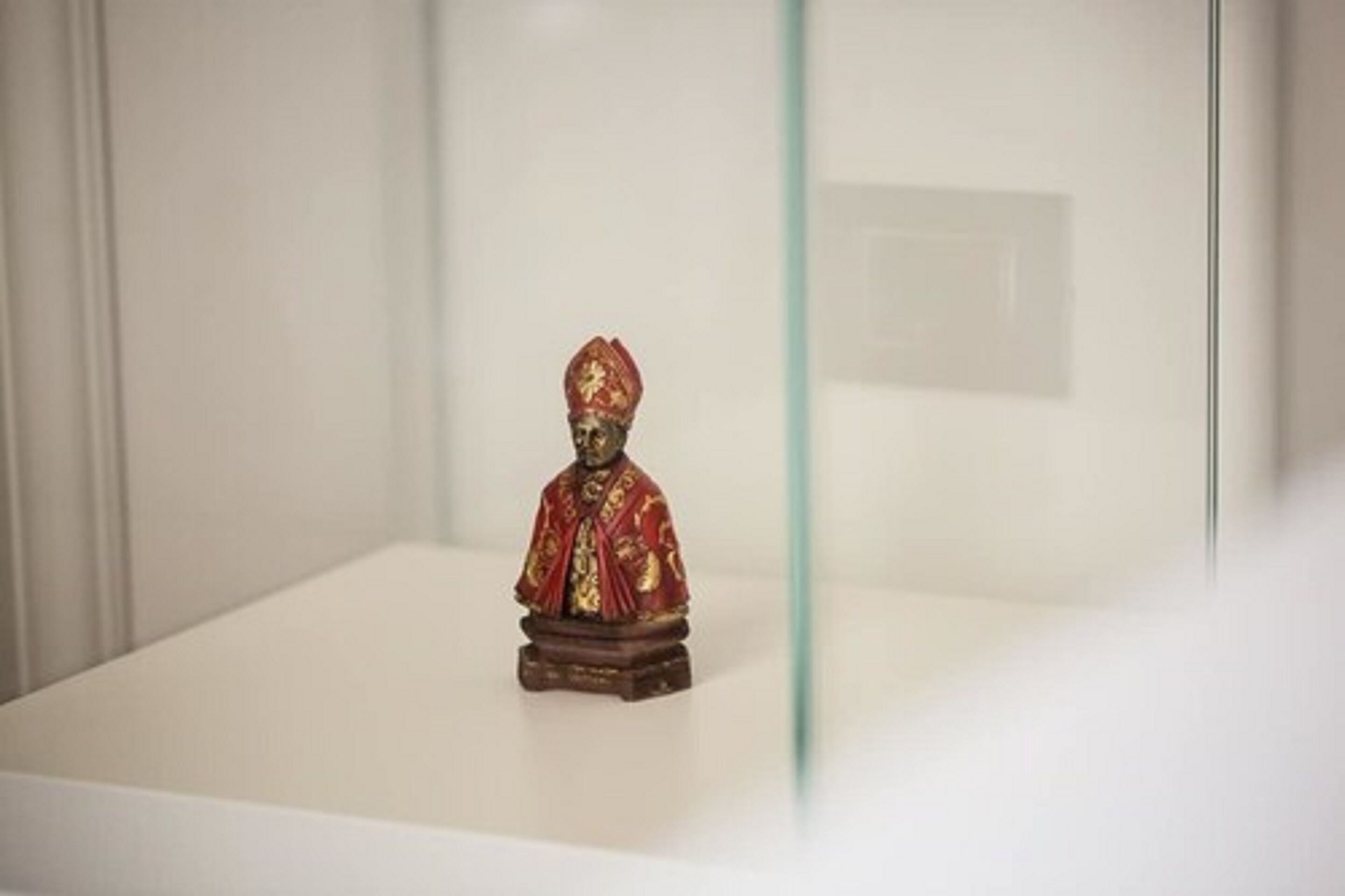 A statue of a person in traditional attire on a pedestal in a museum or gallery setting.