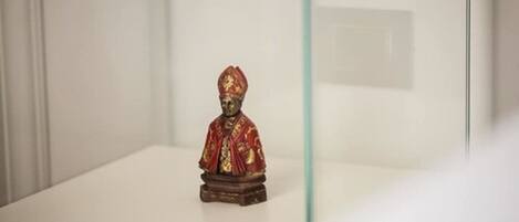 A statue of a person in traditional attire on a pedestal in a museum or gallery setting.