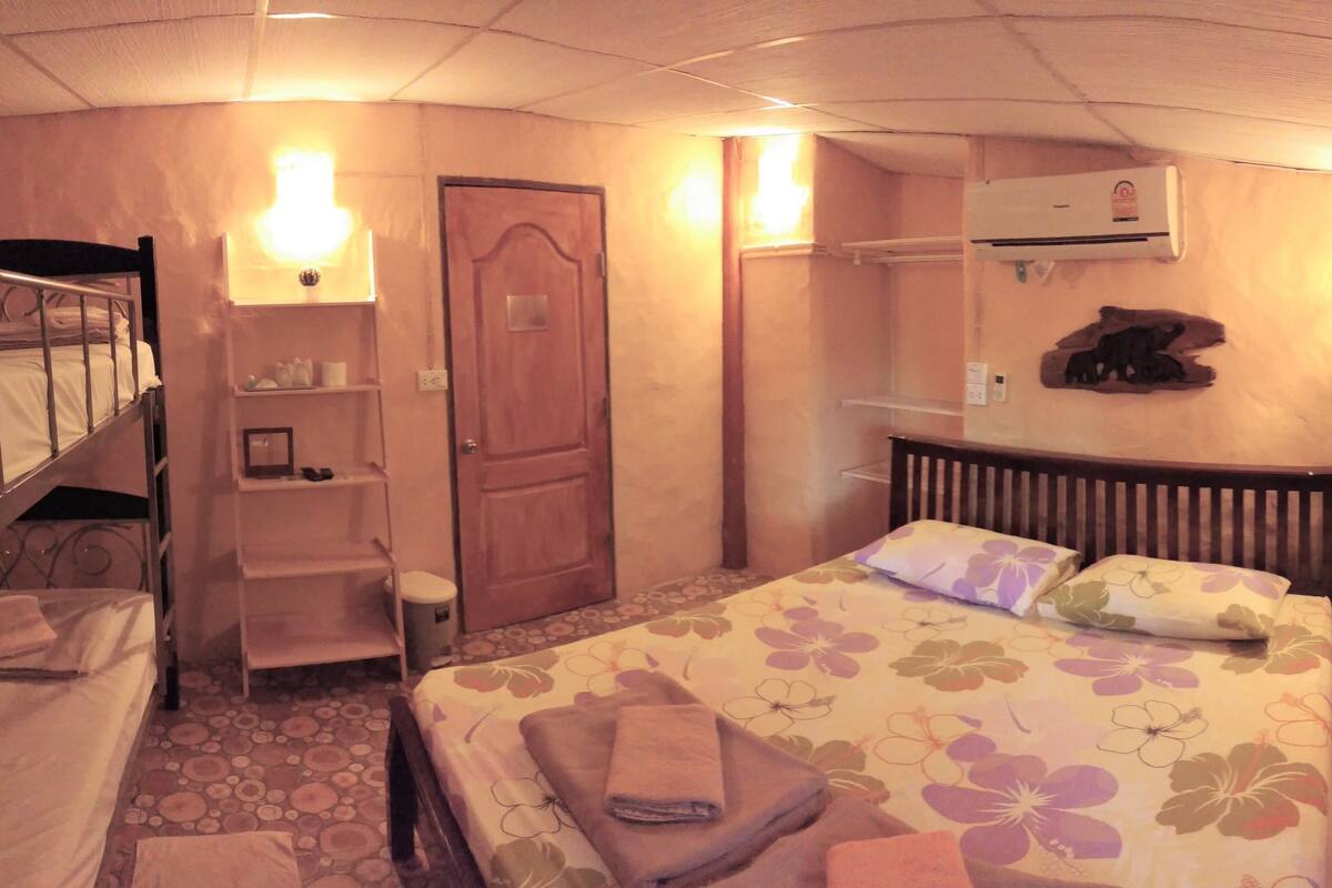 Une chambre à coucher avec un lit, une porte en bois, une étagère et un appareil de climatisation.